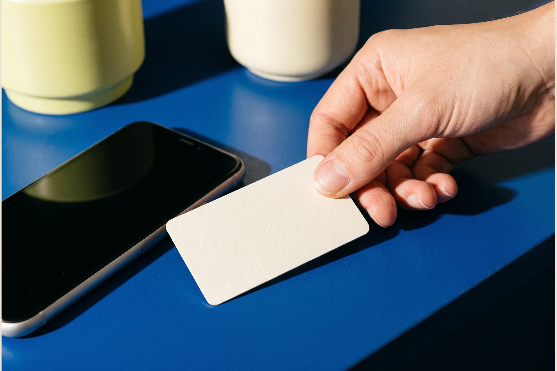 A hand holding a blank card over a phone